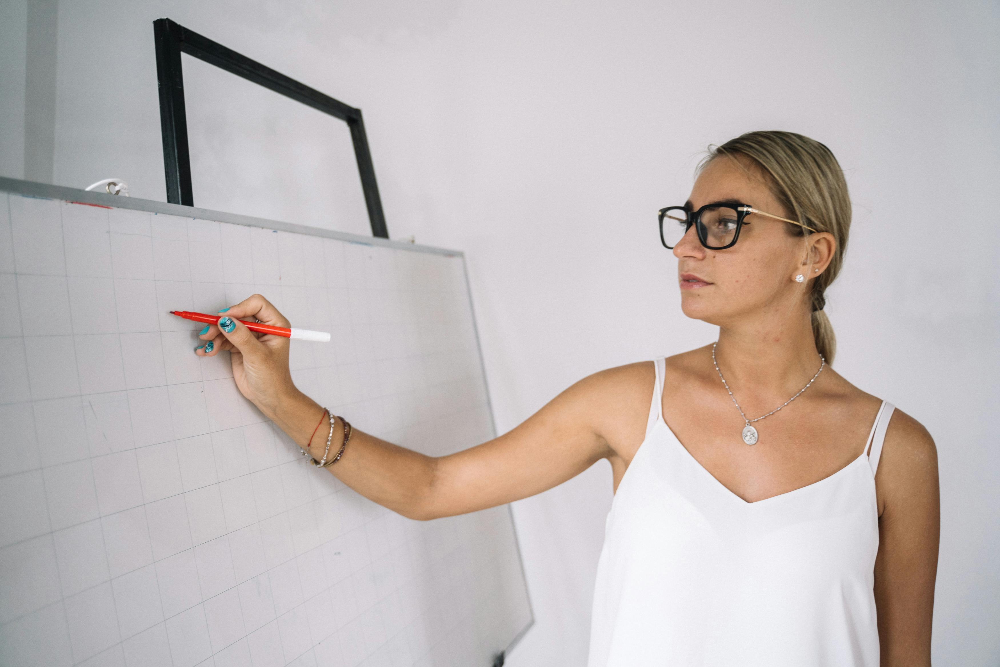 Woman writing on a whiteboard | Source: Pexels